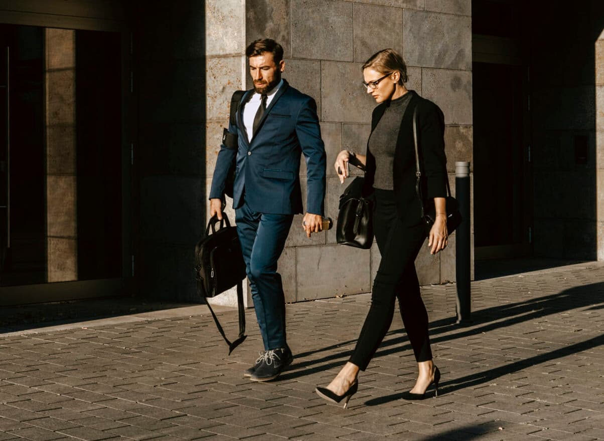Female and male colleagues discussing while walking on footpath in city