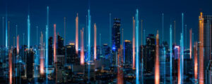 A cityscape at night, with vertical colored lights reaching upward into the sky